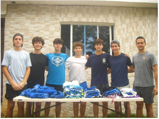 Seven Give & Goal team members standing behind a table stacked with donated soccer uniforms.